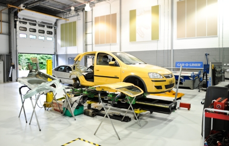 A yellow car in the automotive workshop raised up, with parts removed.