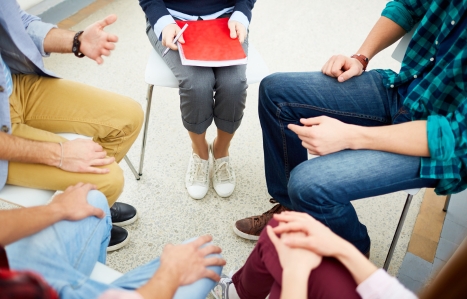 groups of people sat in a circle - only knees and hands in focus