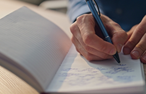 Closeup author hands writing notebook in office