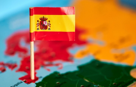 Closeup of a flag of Spain with a small stick on the map