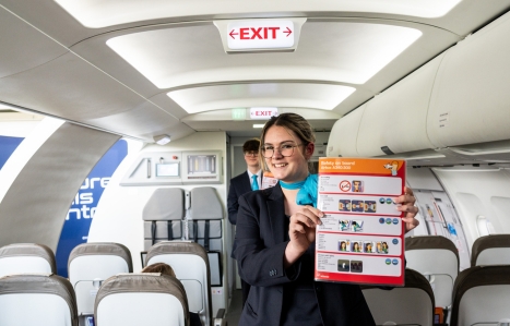 Airline crew smiling at camera with safety manual in mock airline