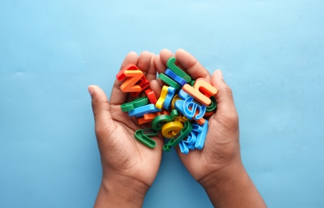 colourful plastic letters on child's hand on blue background