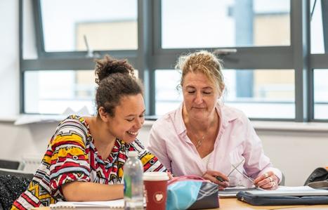 Two students in class smiling at their work