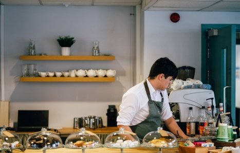 a student behind a counter of food in a restaurant