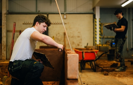 A student bricklayer working on a wall