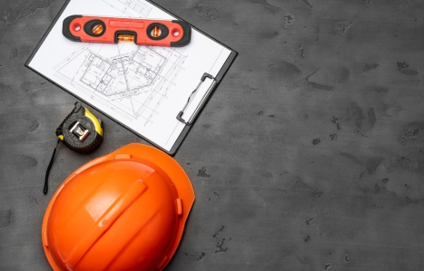 Construction worker hardhat, blueprints and .construction level, top view