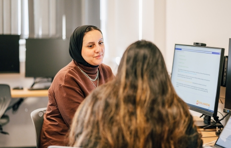 Two students chatting at a computer