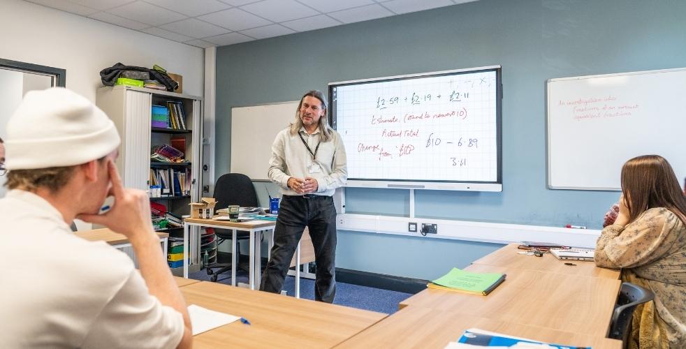 A teacher in front of a whiteboard in a Functional Skills class