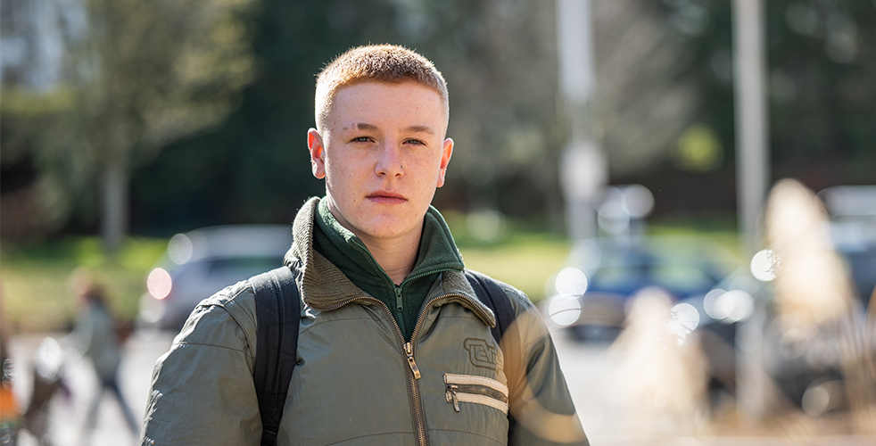 Male Student portrait smiling at the camera wearing a green coat and fleece