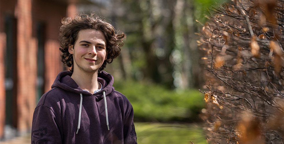 Male Student portrait smiling at the camera wearing a Purple hoodie