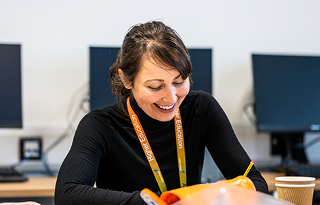 Female student smiling whilst work holding a pencil