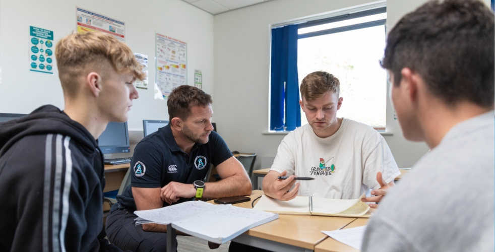 three sports students and a tutor in a classroom