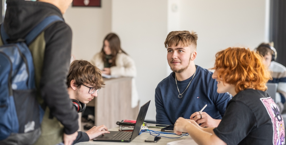 Students in a cafe with laptops chatting