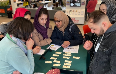 Adult students grouped together playing a game involving maths