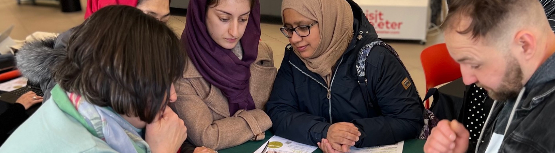 Adults at a community learning session grouped together reading