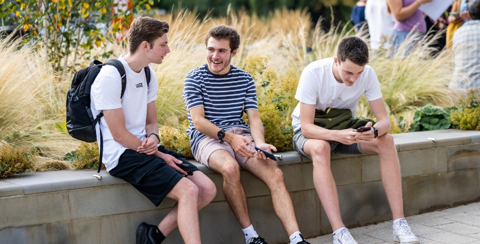 three students sat outside chatting