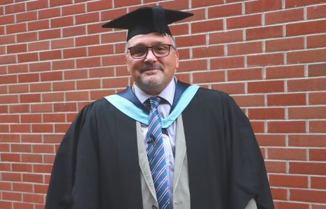 Stewart smiles at the camera in his graduation gown