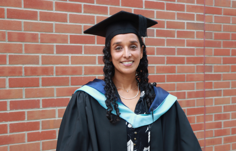 Emma smiles at the camera in her graduation gown.