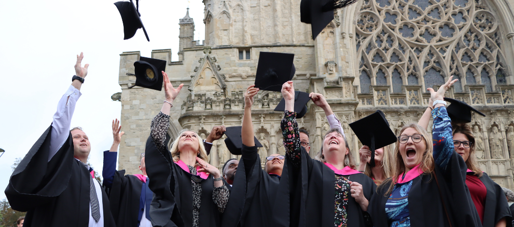 Graduating students throw their caps in the air outside Exeter Cathedral.