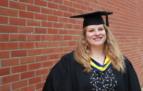 Molly smiles at the camera in her graduation gown.