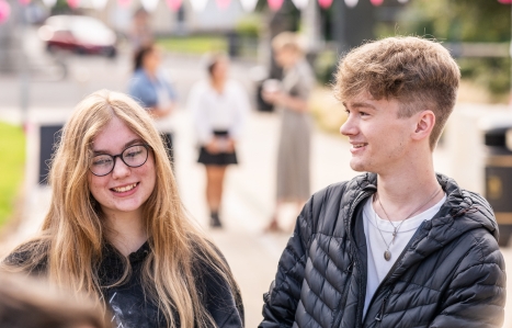Two students outside college smiling