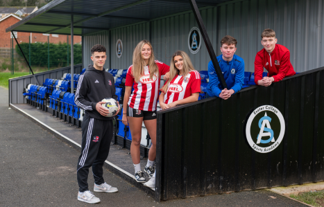 Exeter City Football Club players and Exeter College Sports Academy players lean on the new spectator seating at Exwick Sports Hub.
