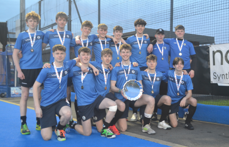 The Men's U18 hockey team hold up their trophy and smile at the camera