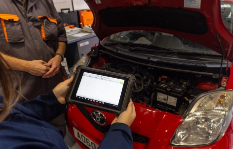 image of a red car bonnet open and an electronic diagnostic device