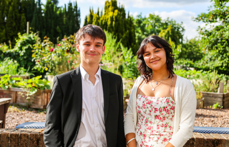 A male and female student stand in the herb garden