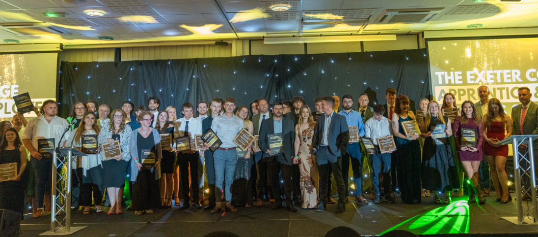 Award winners at the Apprentice and Employer Awards stand on stage with their trophys