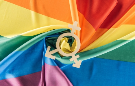 top view of rainbow flag creased in spiral shape with gender sign