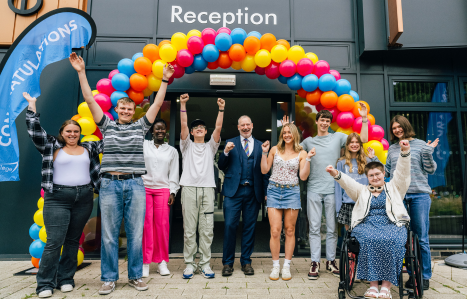 Exeter College students stand under a balloon arch and celebrate results