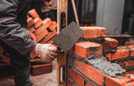 Bricklayer puts bricks to make a wall