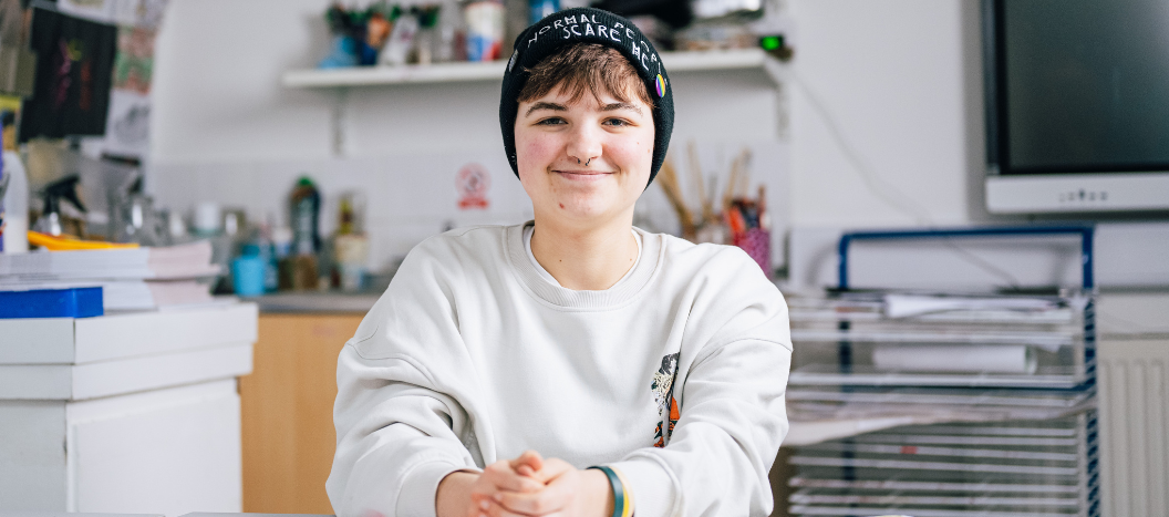 Student Sat in an art room smiling directly at the camera