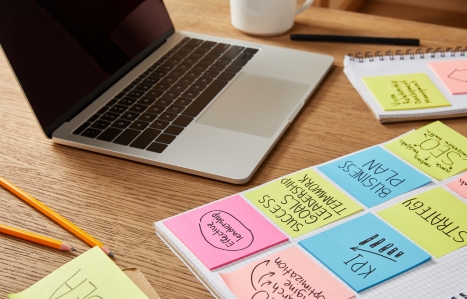 paper stickers with business strategy and laptop on wooden tabletop