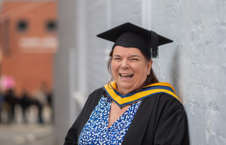 A female mature graduate smiles at the camera