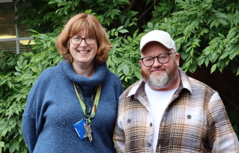 Tutor and student stand together and smile at the camera.