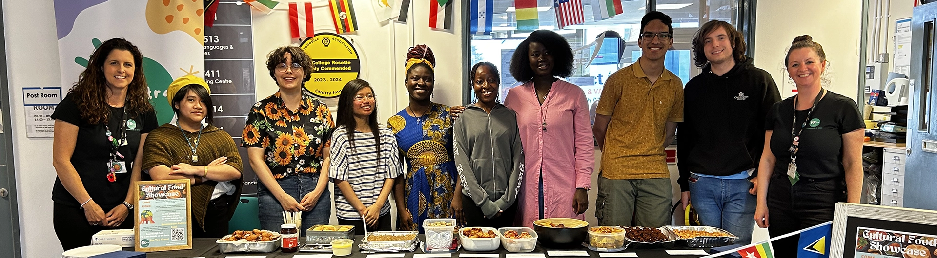 Group photo of one of the extra teams stood in front of a table filled with meals from all over the world 