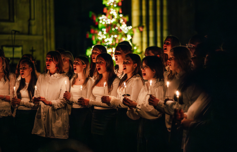 Students sing by candelight in Exeter Cathedral