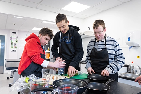 Three HILL students cooking together in a kitchen