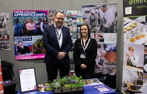 Photo of a staff member and employer at a stand at the Expo smiling at the camera