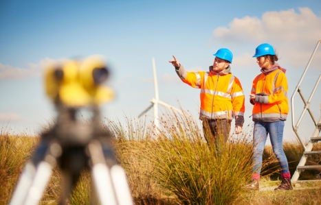 Two workers in a field working with Hard hats and orange high vis