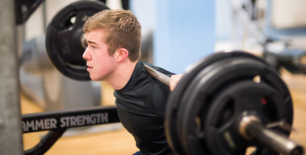 Male student using weights in the gym