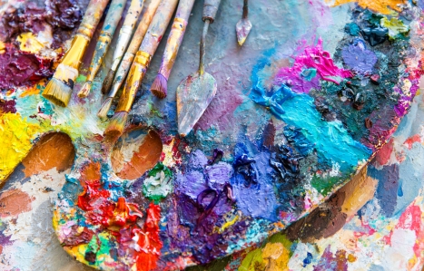 Art palette with colourful mixed paints and paintbrushes