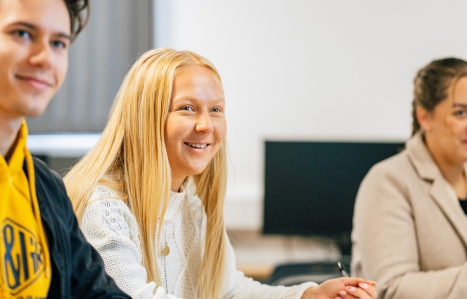 three students in class smiling looking up