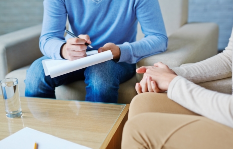 A counsellor with a clipboard talking to someone