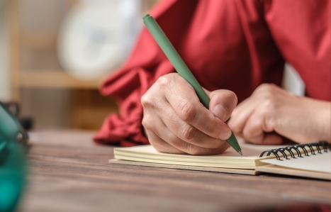 close up hand writing on notebook on wooden table