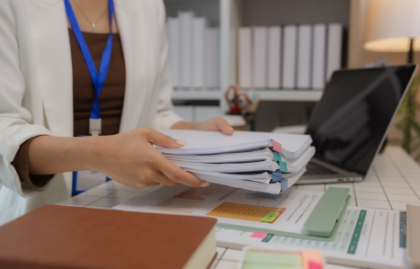 focus on someone holding a large pile of papers at a desk