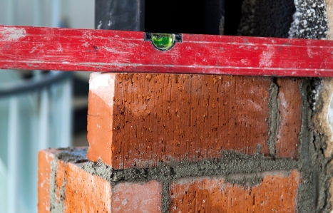 Close up of bricklaying industrial installing bricks on construction site wall with working tools