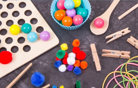 Colourful pompoms, balls and rubber erasers using for development of kids motor skills